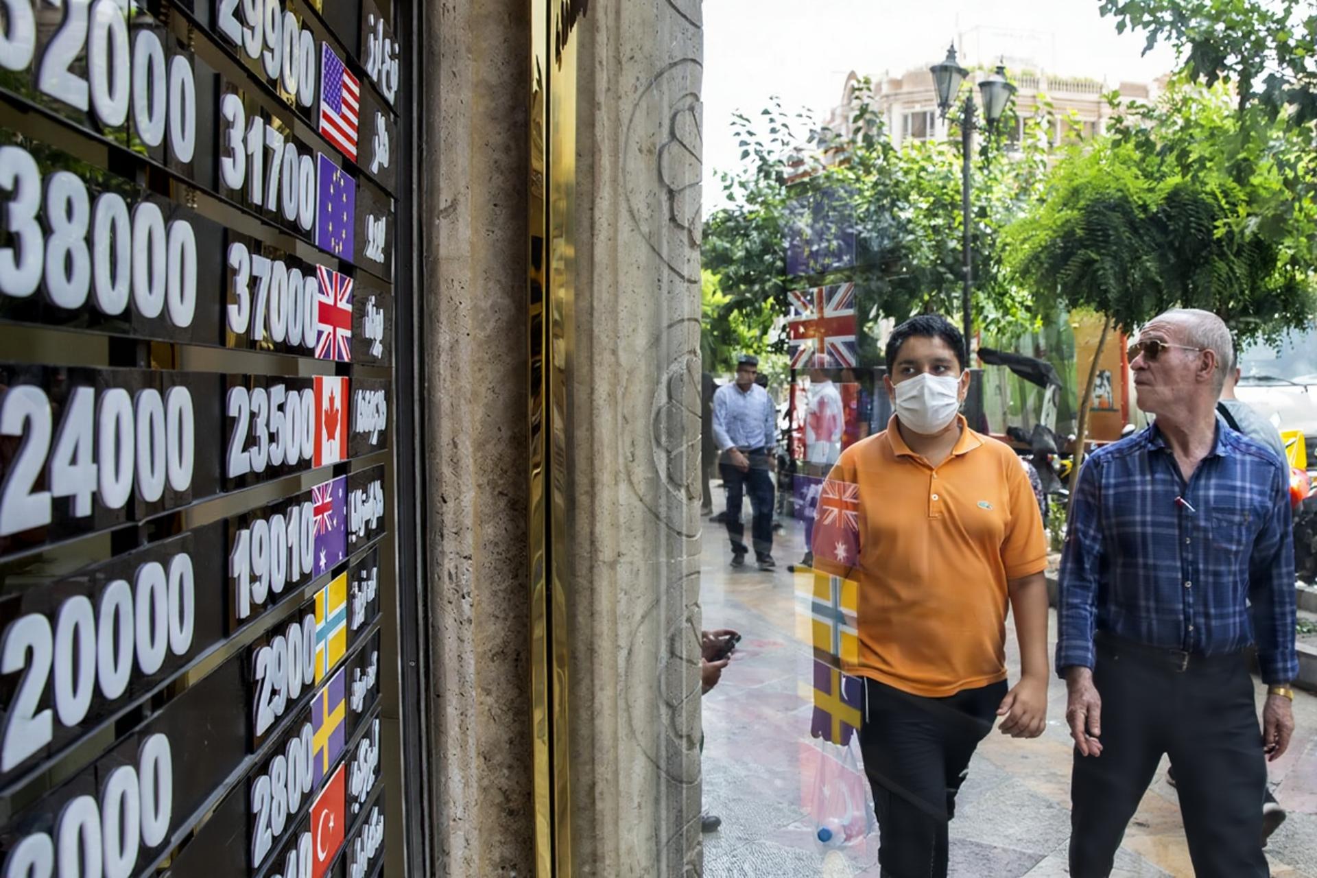 دو رهگذر در حال تماشا تابلو قیمت ارز یک صرافی در راسته فردوسی 