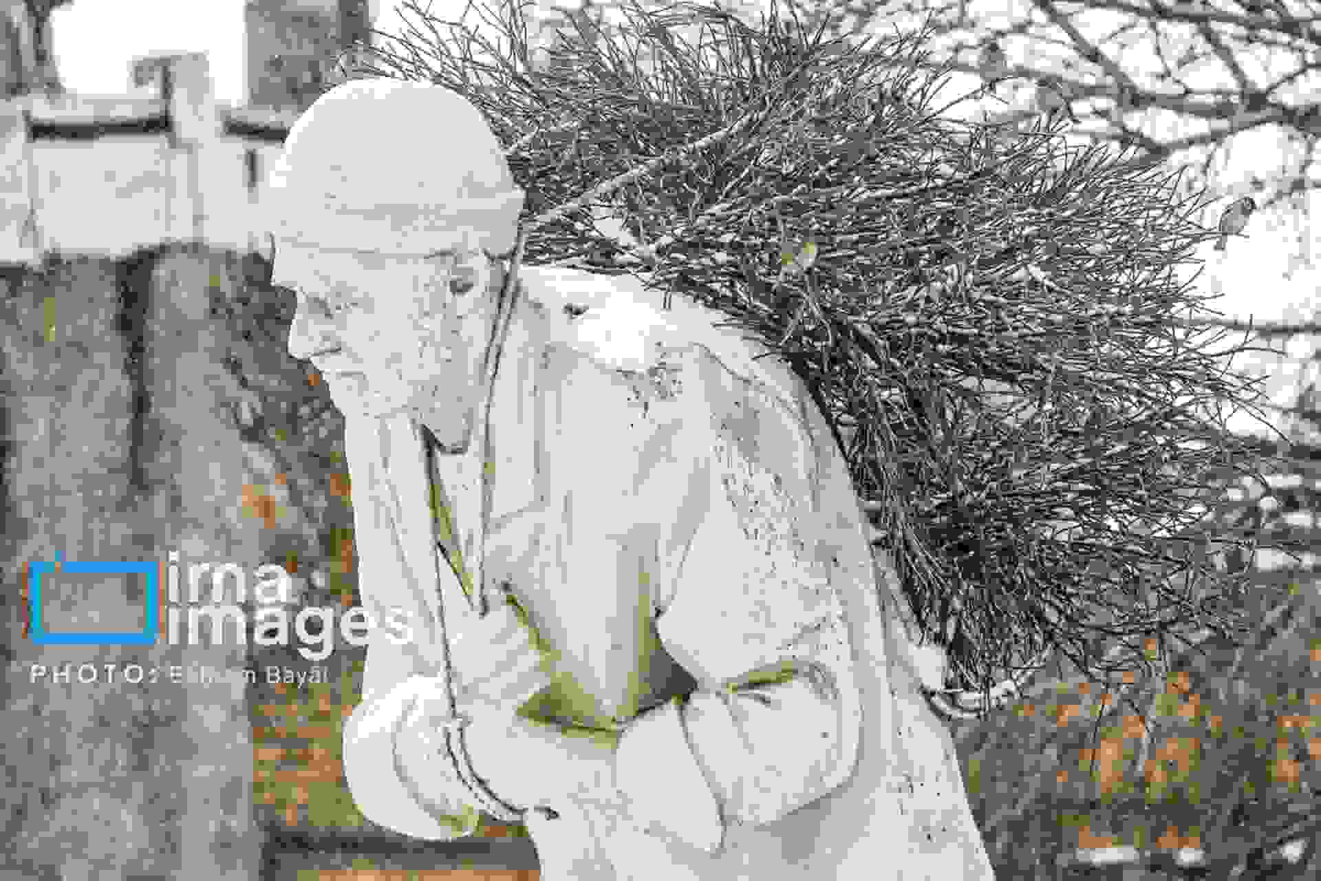 مجسمه‌ای نمادین از یک مرد سالخورده خار بر پشت در یک روزی برفی