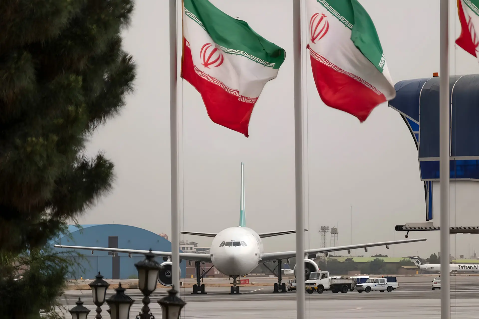 هواپیمای مسافربری در باند فرودگاه در کنار پرچم‌های ایران