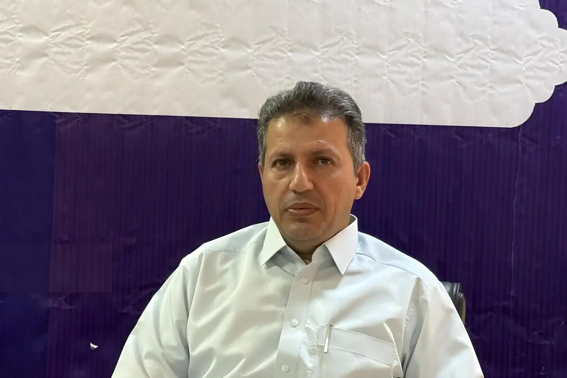 مردی با پیراهن سفید در مقابل پس‌زمینه‌ی بنفش و سفید
