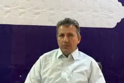 مردی با پیراهن سفید در مقابل پس‌زمینه‌ی بنفش و سفید