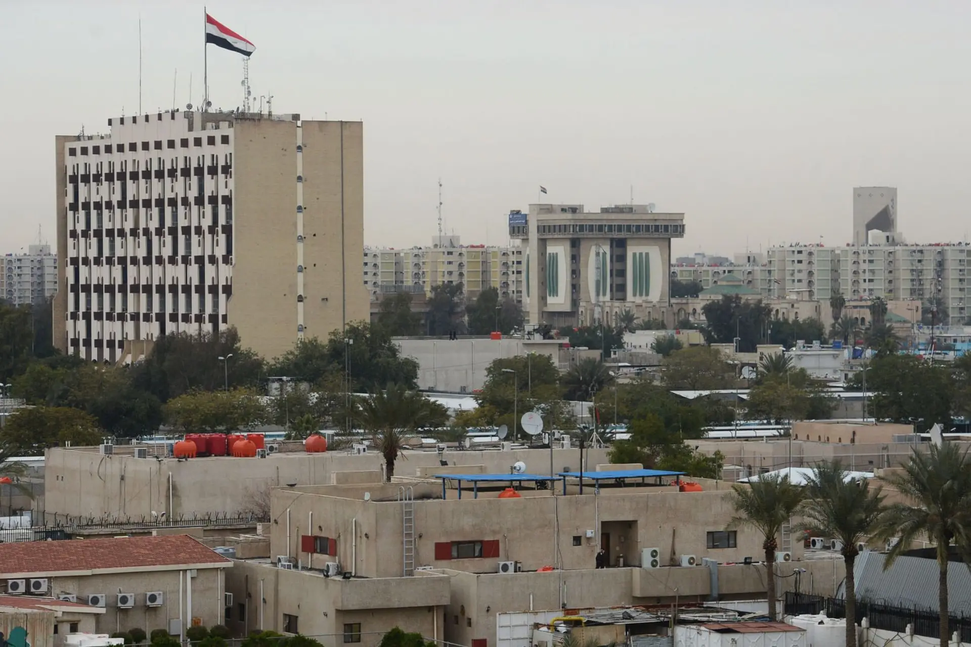 ساختمان‌های شهری در بغداد (Baghdad) با پرچم عراق بر فراز یک بنای مرتفع