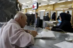 مرد مسن در حال پر کردن فرم بانکی پشت میز خدمات مشتریان