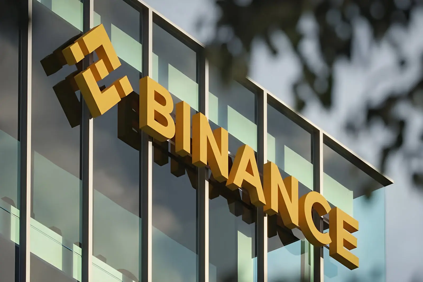 لوگوی طلایی صرافی بایننس (Binance) روی نمای شیشه‌ای ساختمان