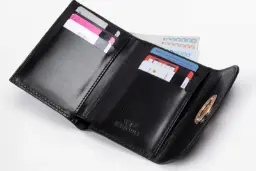 کیف پول چرمی مشکی باز شده حاوی اسکناس‌های پول