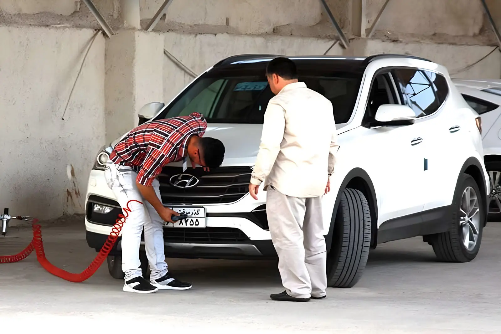 بازرسی فنی خودروی کراس‌اوور سفید (Hyundai) توسط کارشناسان در کارگاه