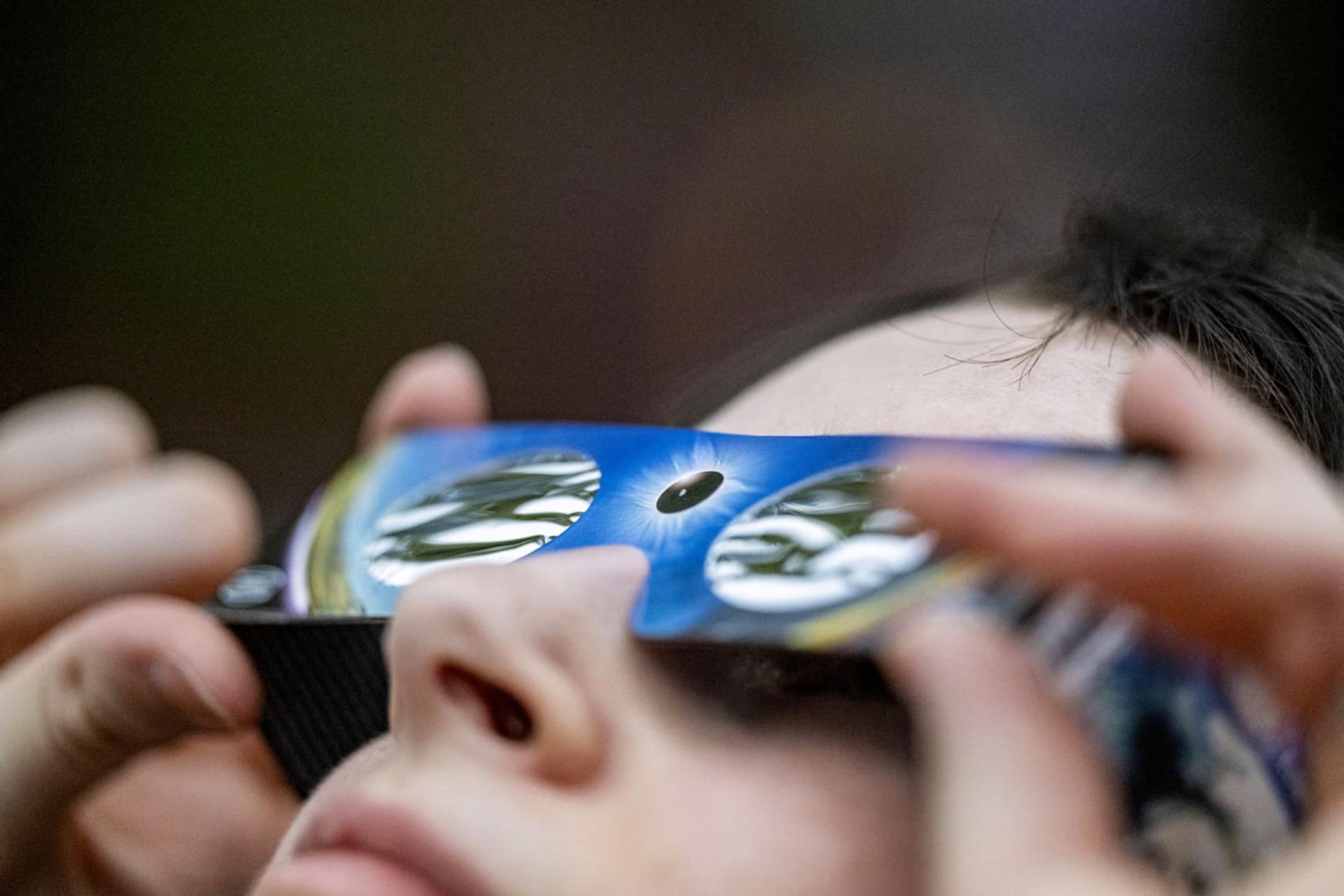 عینک مشاهده خورشید (Solar Eclipse Glasses) روی چشم‌های یک کودک قرار گرفته است