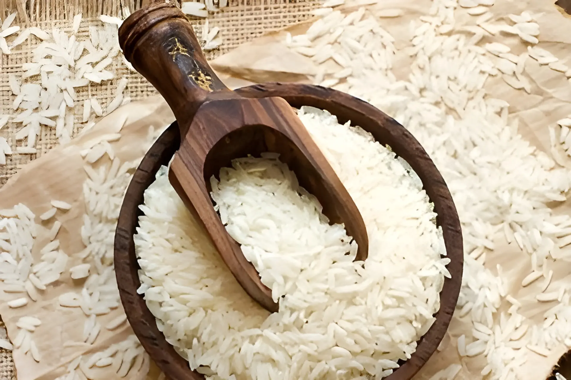 برنج سفید در ظرف چوبی و پیمانه چوبی روی کاغذ