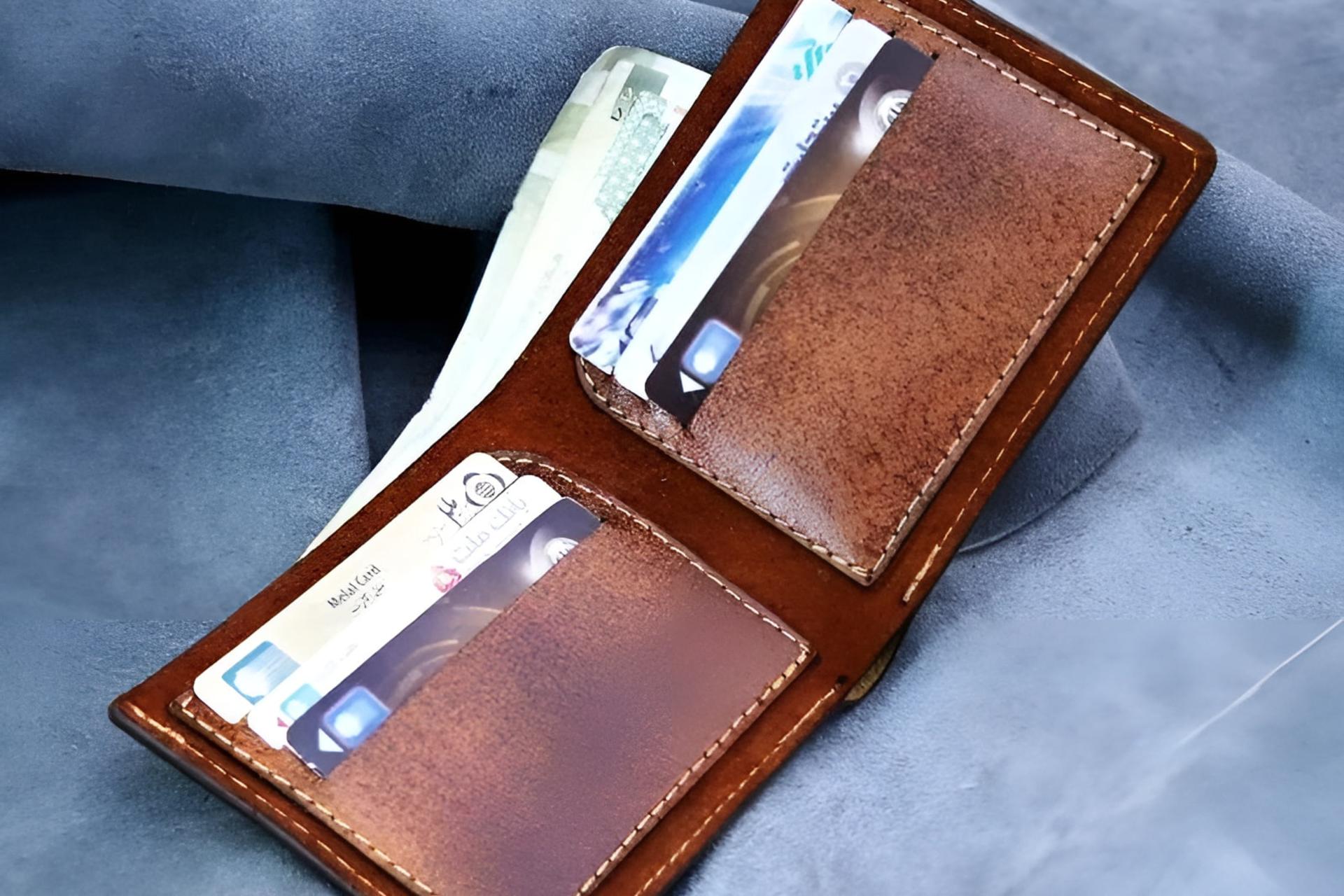 کیف پول چرمی باز شده حاوی کارت‌های بانکی و اسکناس