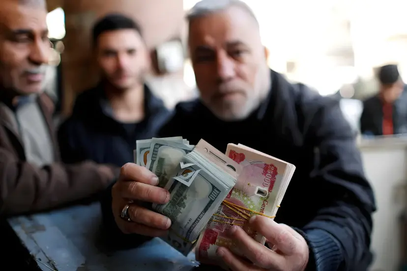 دست‌های مردی در بازار تبادل ارز بغداد با دسته‌های اسکناس دلار و دینار