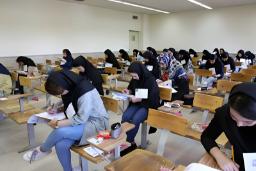 داوطلبان کنکور در حال پاسخ‌دهی به سوالات در یک سالن امتحانی
