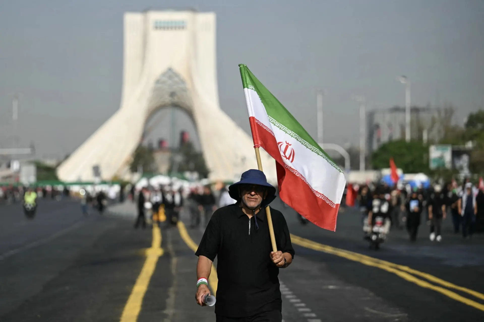 پرچم ایران (Flag of Iran) در دست مردی در میدان آزادی تهران