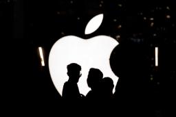 لوگوی اپل (Apple) در شب در مقابل سایه چند نفر