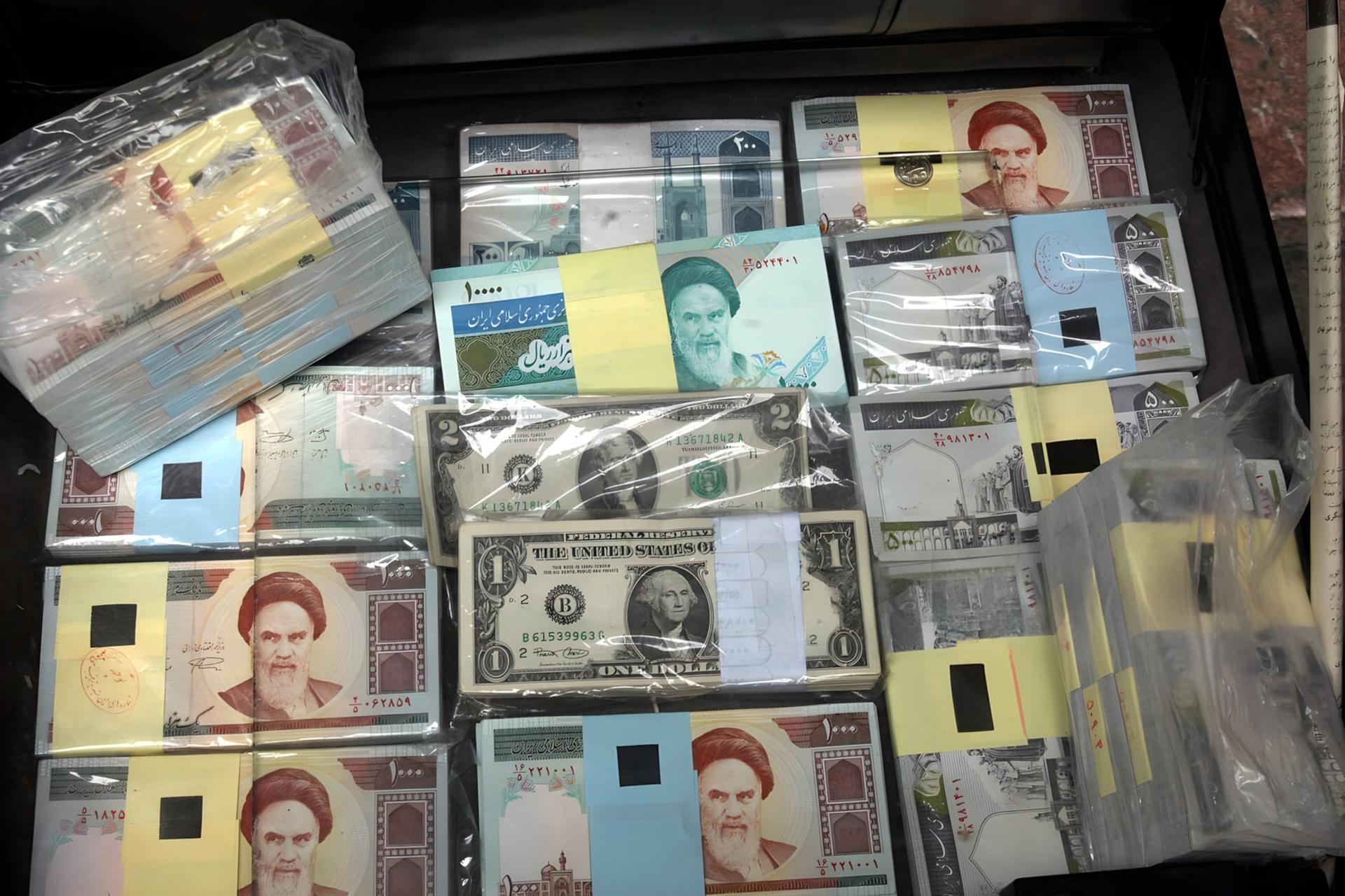 رزمه‌های اسکناس‌های ریال ایران و اسکناس‌های دلار آمریکا (US Dollar) در کنار هم