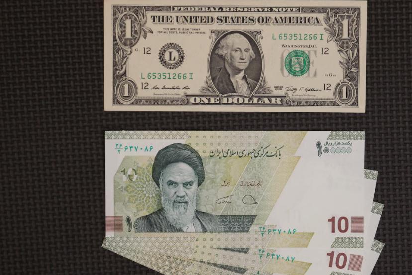 اسکناس یک دلاری آمریکا (US Dollar) و اسکناس‌های ده هزار ریالی ایران روی میز