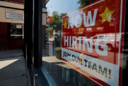 برگه استخدام نیروی جدید با نوشته NOW HIRING روی شیشه ویترین مغازه