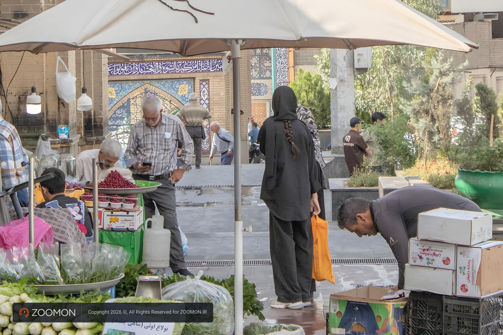 بازار سنتی با دکه‌های میوه و سبزیجات و مشتریان در حال خرید