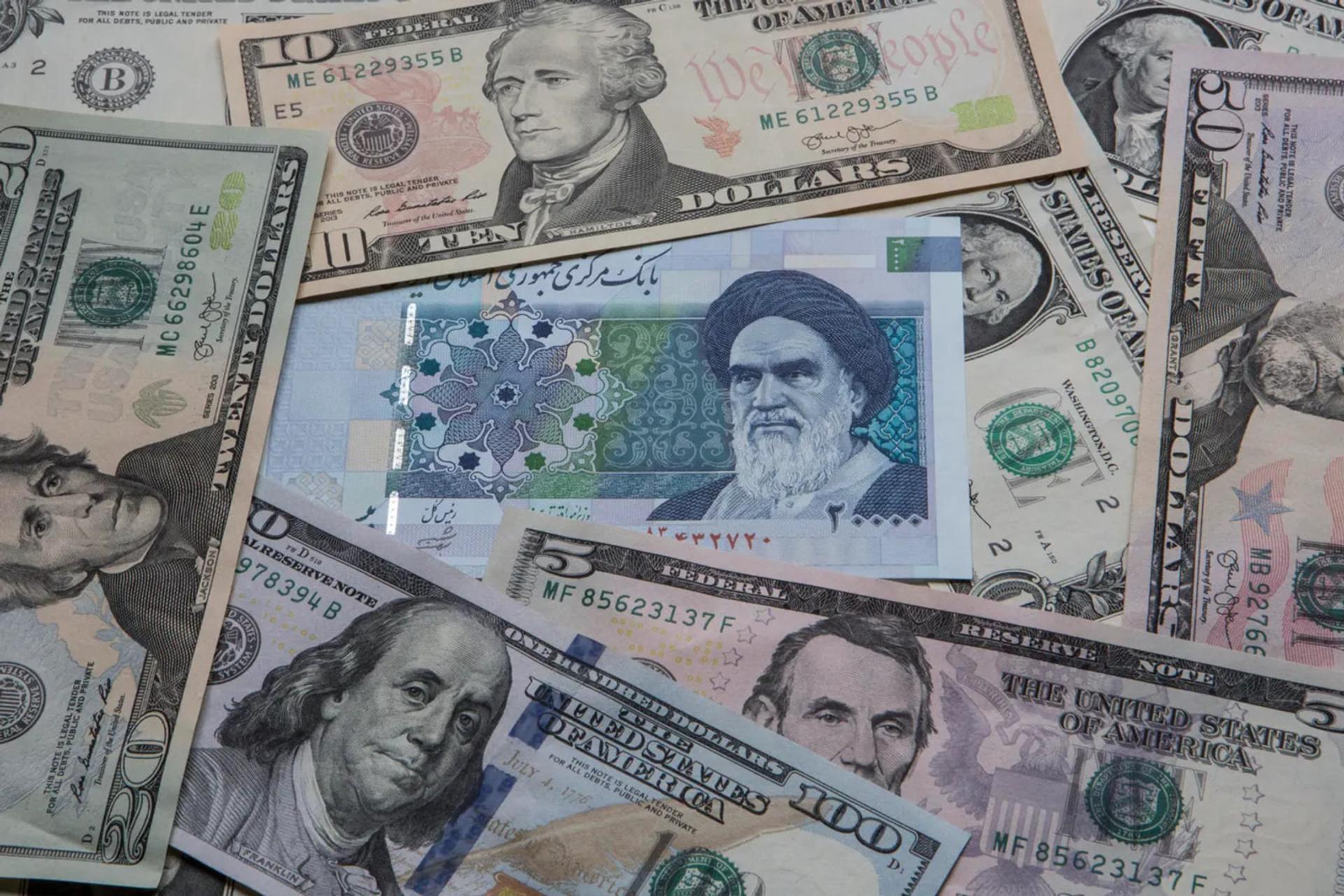 اسکناس‌های دلار آمریکا و پول ملی ایران (Rial) روی هم قرار گرفته‌اند