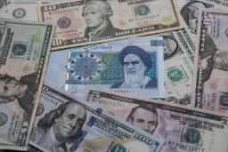 اسکناس‌های دلار آمریکا و پول ملی ایران (Rial) روی هم قرار گرفته‌اند