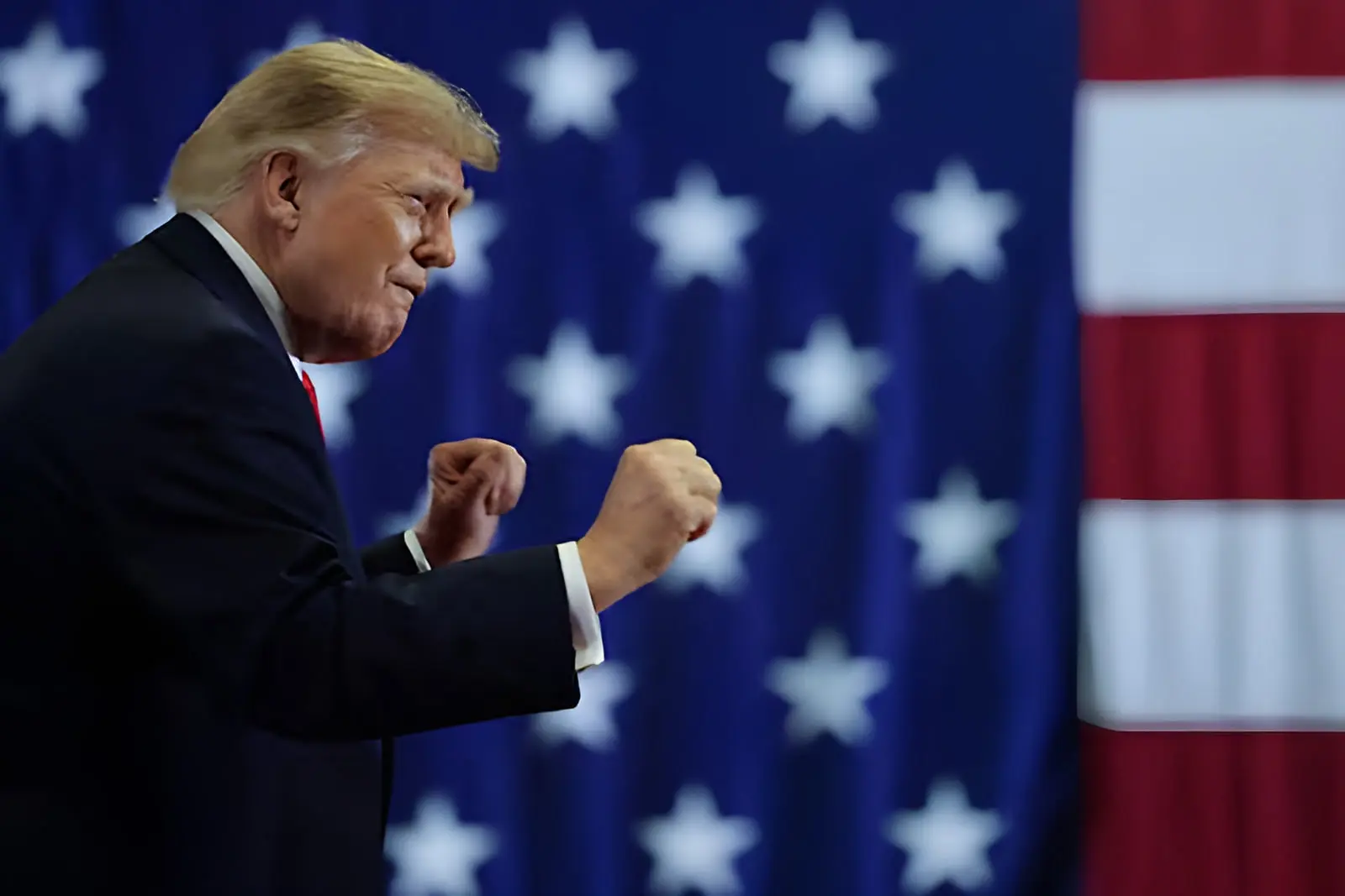دونالد ترامپ (Donald Trump) با مشت‌های گره‌کرده در مقابل پرچم ایالات متحده