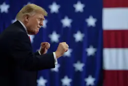 دونالد ترامپ (Donald Trump) با مشت‌های گره‌کرده در مقابل پرچم ایالات متحده