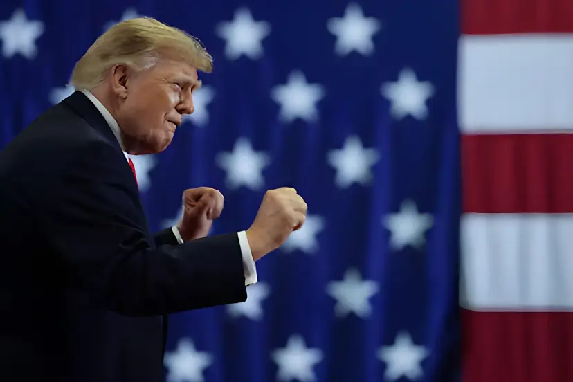 دونالد ترامپ (Donald Trump) با مشت‌های گره‌کرده در مقابل پرچم ایالات متحده