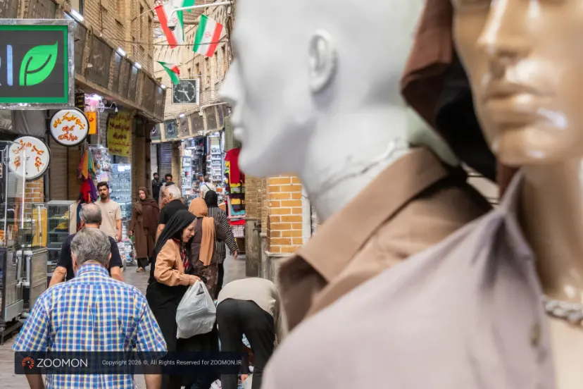 بازار شلوغ تهران با مانکن‌های لباس در پیش‌زمینه و عابرانی در پس‌زمینه