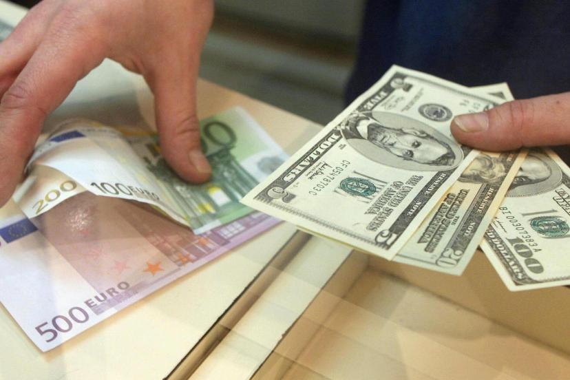 دست‌های یک فرد در حال جابه‌جایی و شمارش اسکناس‌های یورو و دلار آمریکا روی میز است.