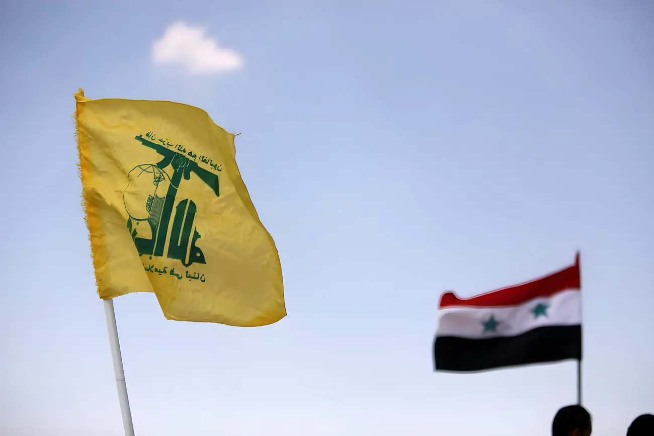 پرچم زرد حزب‌الله (Hezbollah) و پرچم سوریه در مقابل آسمان آبی