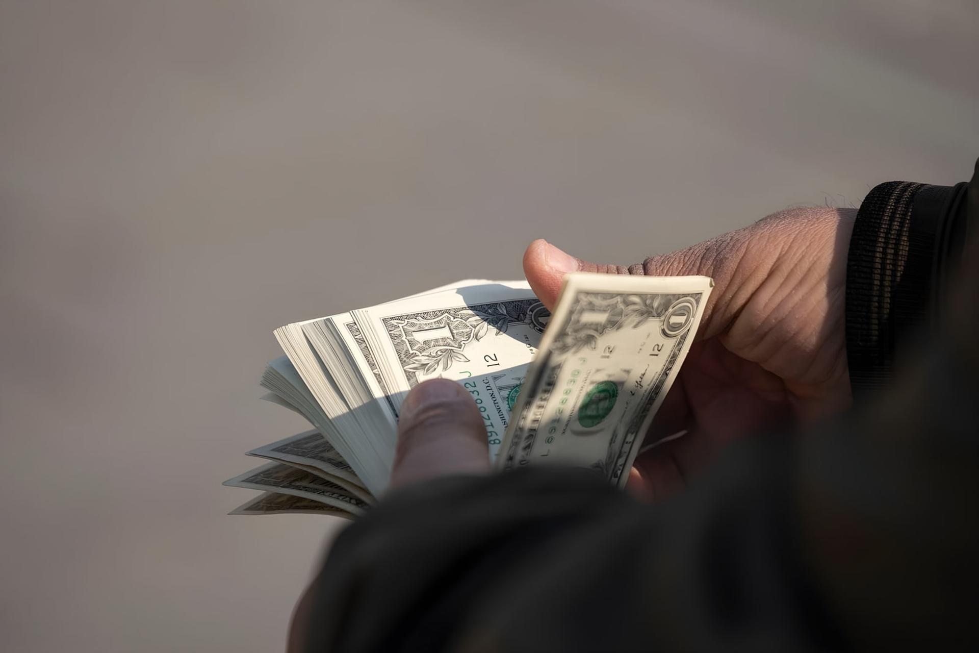 اسکناس‌های دلار (US Dollar) در دستان یک فرد
