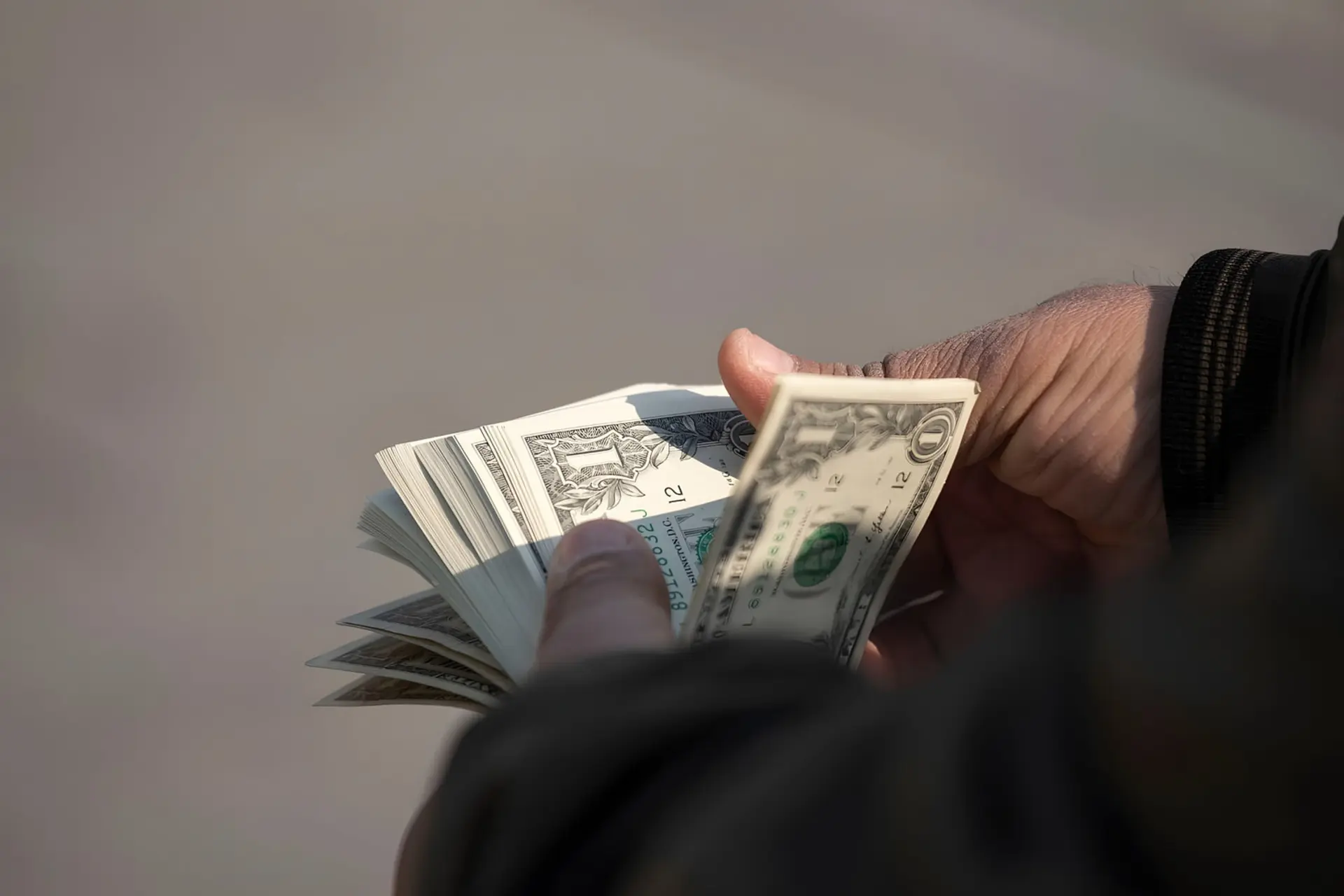 اسکناس‌های دلار (US Dollar) در دست فردی برای مبادله در بازار