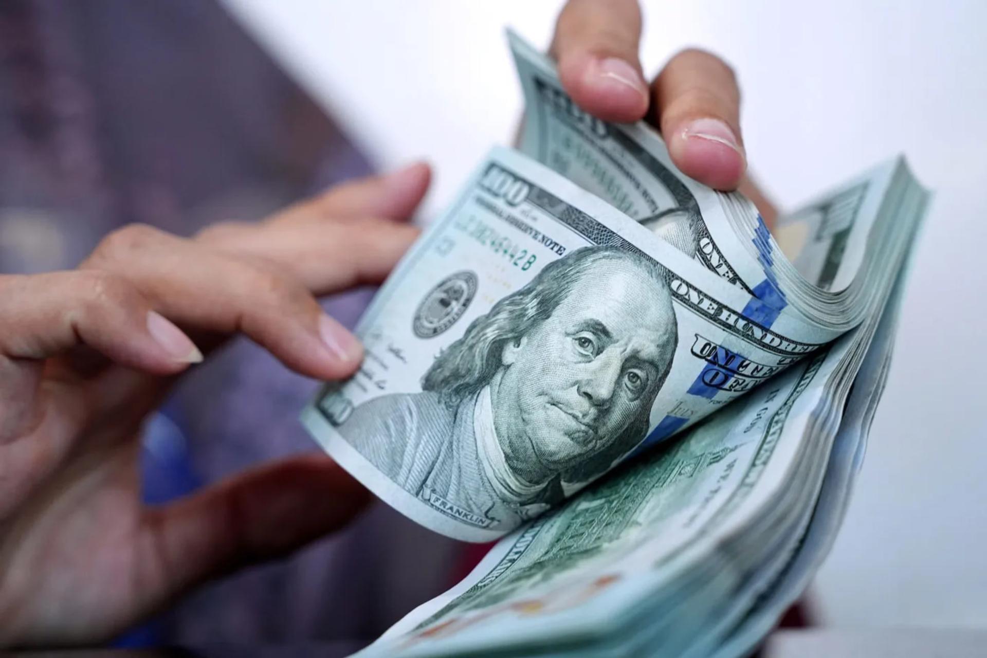 اسکناس‌های صد دلاری (US Dollar) در دست‌های یک فرد