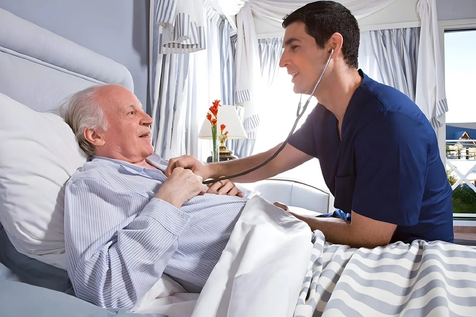 پزشک با گوشی پزشکی در حال معاینه بیمار مسن در تخت خواب