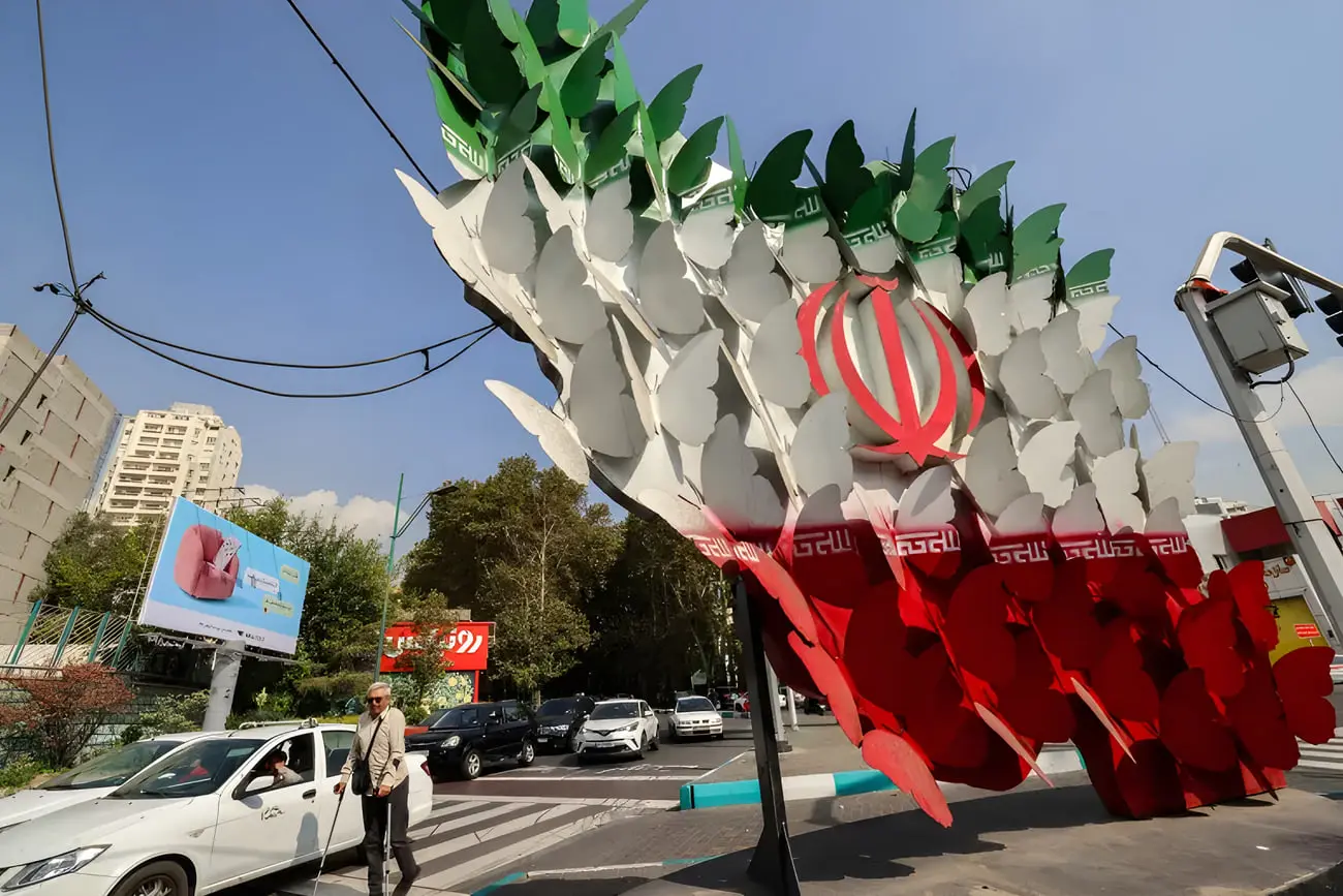 مجسمه بزرگ پرچم ایران (Flag of Iran) در تقاطع خیابانی با خودروهای در حال حرکت