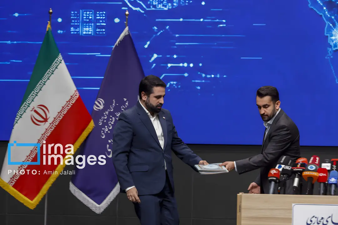 دو مرد در حال تبادل اسناد در نشست مربوط به طرح صیانت اینترنت