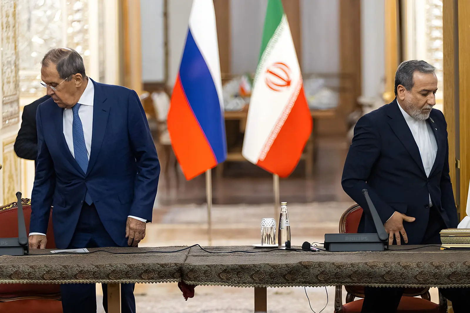 سرگئی لاوروف (Sergey Lavrov) و مقام ایرانی در نشست دیپلماتیک در حضور پرچم‌های ایران و روسیه