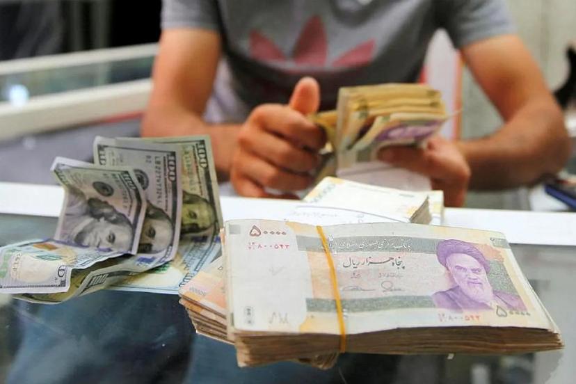 نمایی از دسته‌های اسکناس ریال ایران و اسکناس‌های صد دلاری آمریکا روی میز صرافی