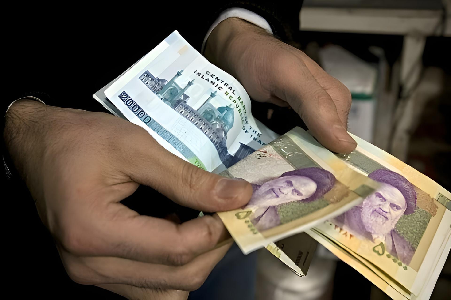 اسکناس‌های ریال ایران در دستان یک فرد برای پرداخت یا شمارش