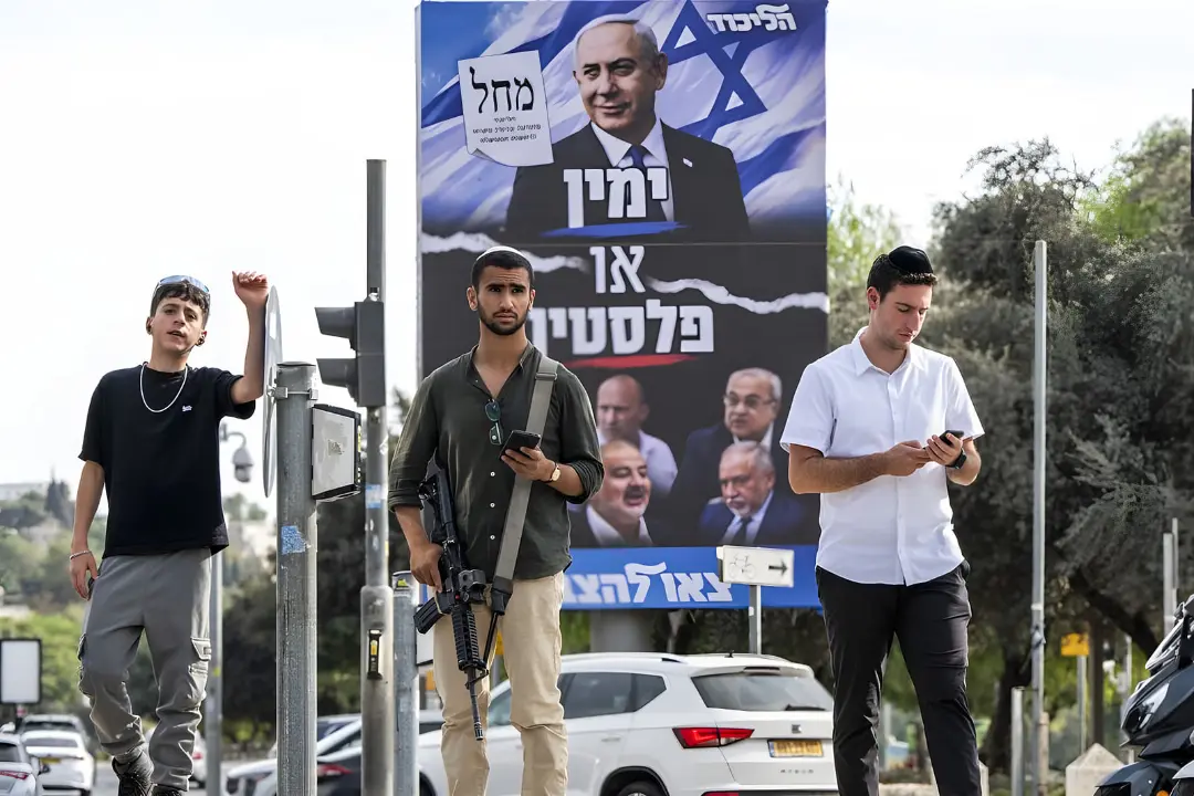 سرباز مسلح و جوانان در کنار بیلبورد تبلیغاتی بنیامین نتانیاه (Benjamin Netanyahu)