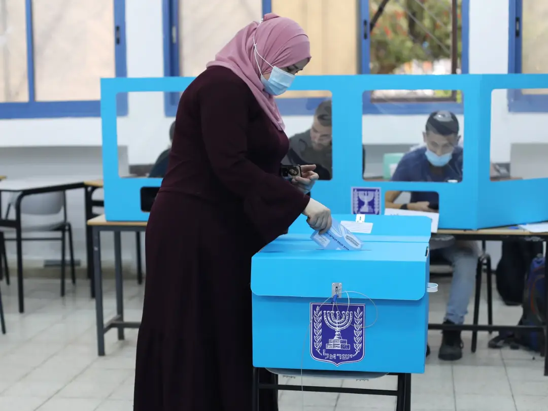 زن با حجاب در حال انداختن برگه رای در صندوق انتخابات اسرائیل