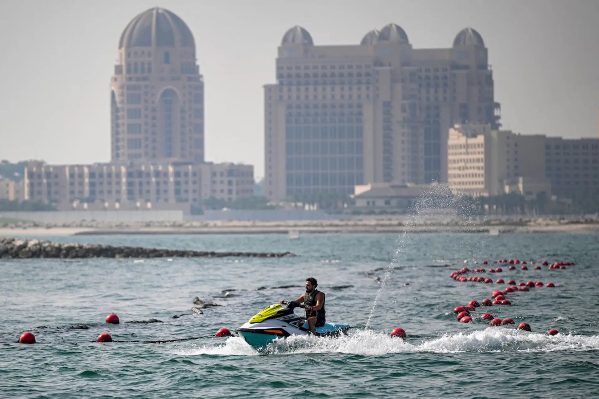 سواری با جت‌اسکی (Jet Ski) در آب‌های دریا با پس‌زمینه ساختمان‌های بزرگ