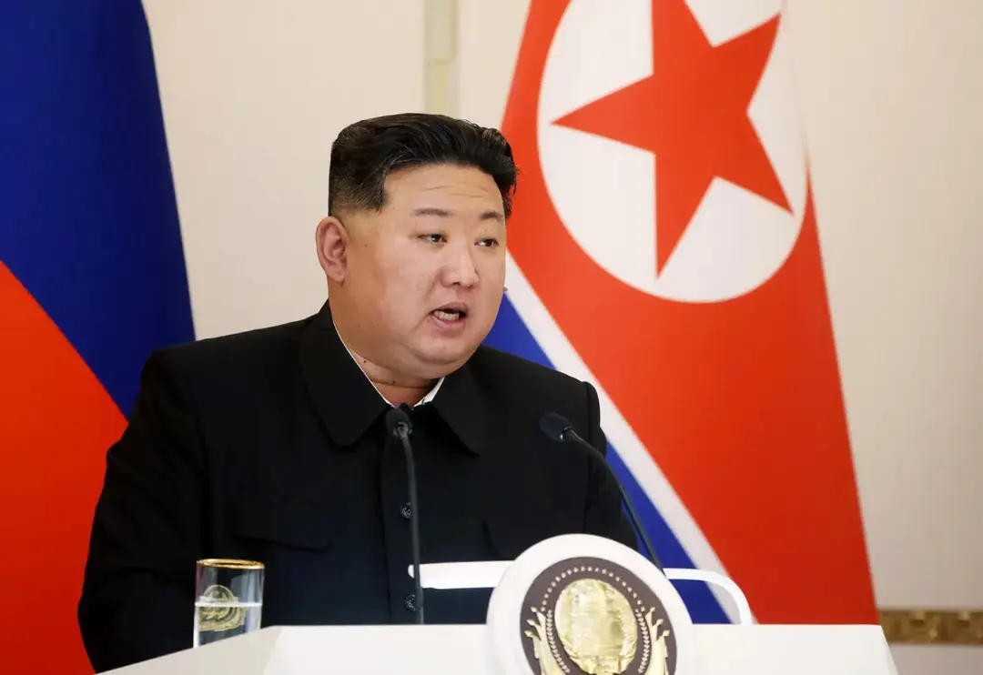 کیم جونگ اون (Kim Jong Un) پشت تریبون در کنار پرچم کره شمالی