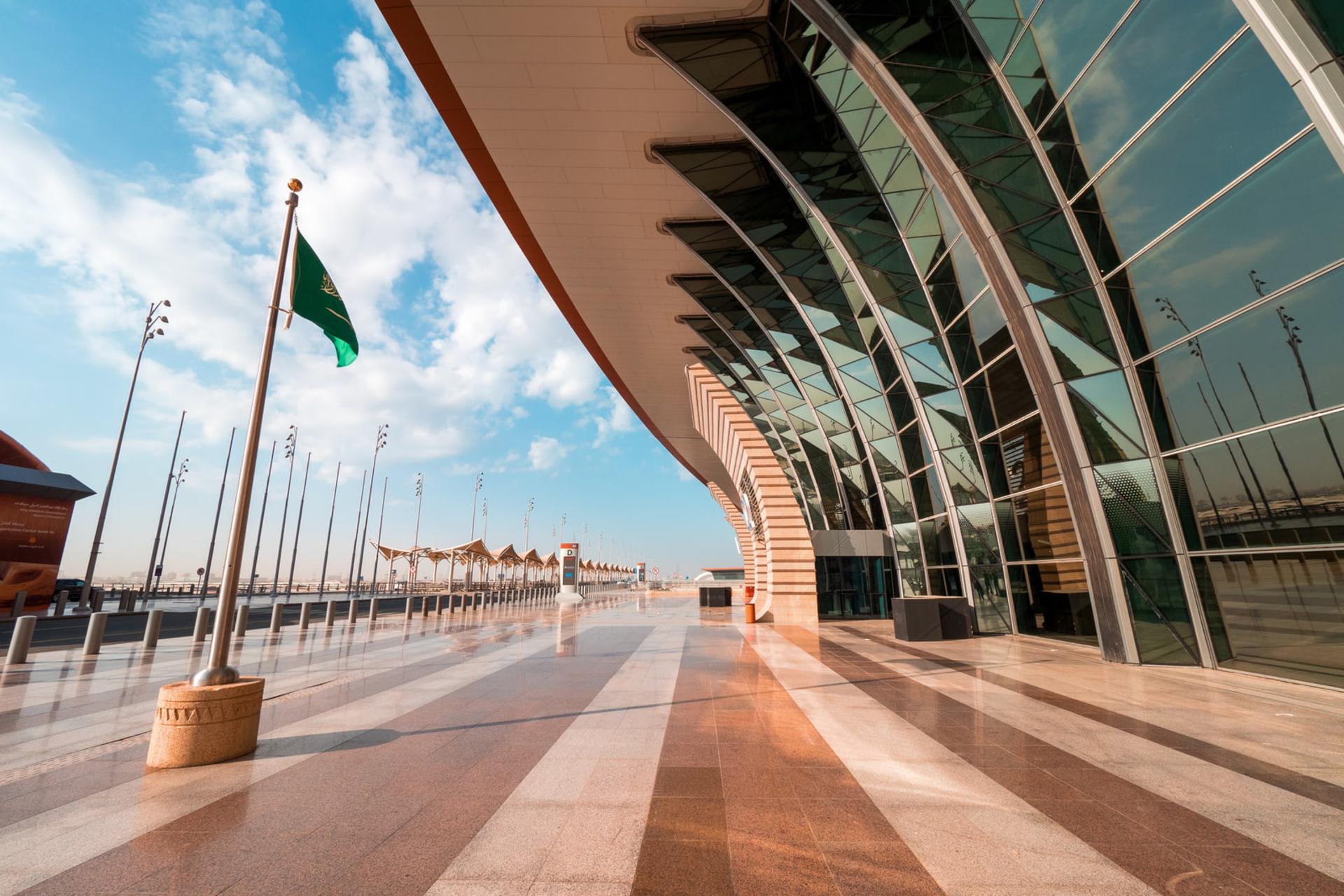 ساختمان مدرن فرودگاه ملک خالد (King Khalid Airport) با نمای شیشه‌ای و پرچم عربستان