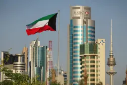 پرچم کویت (Kuwait Flag) در مقابل آسمان و ساختمان‌های بلند شهر
