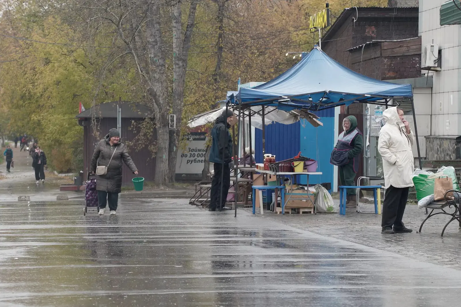بازار محلی در خیابانی بارانی در روسیه با دکه‌های فروشندگی