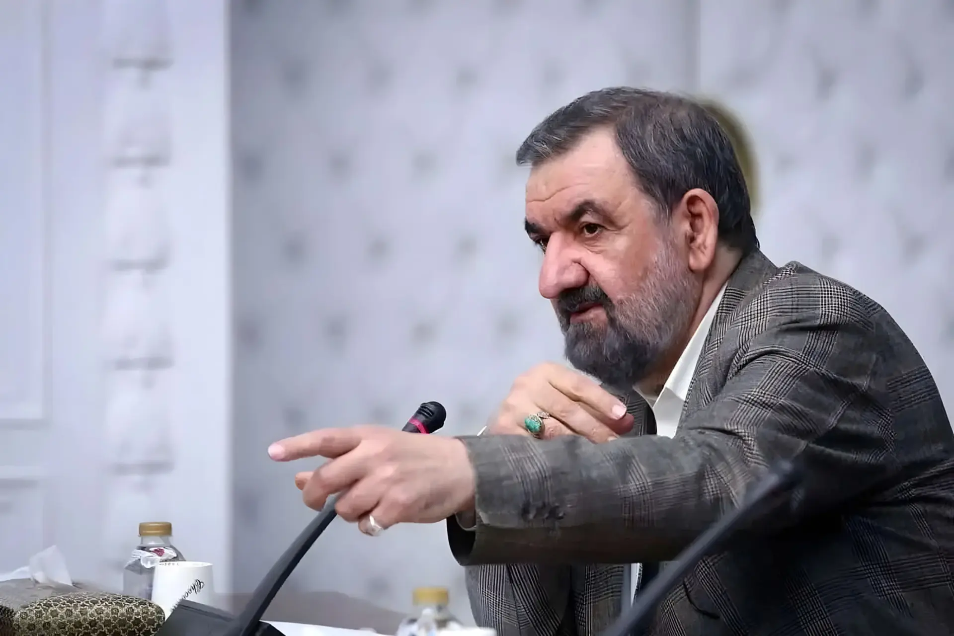 مردی میانسال با ریش تیره در حال صحبت با میکروفون