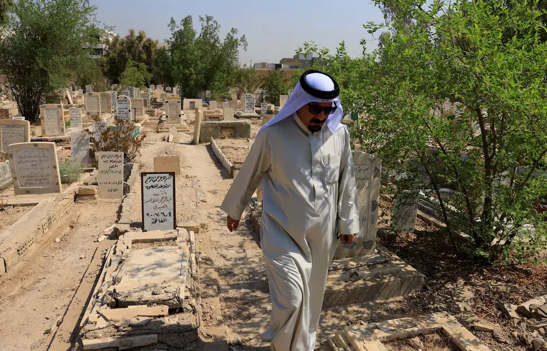 مردی با لباس سنتی در میان مزارهای قدیمی یک قبرستان در عراق