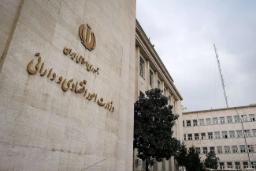 نمای نمای بیرونی ساختمان وزارت امور اقتصادی و دارایی ایران با نشان رسمی جمهوری اسلامی روی دیوار سنگی.