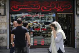 نمای جلوی صرافی محسن با تابلوهای دیجیتال نمایش قیمت ارز و عابران پیاده در مقابل آن.
