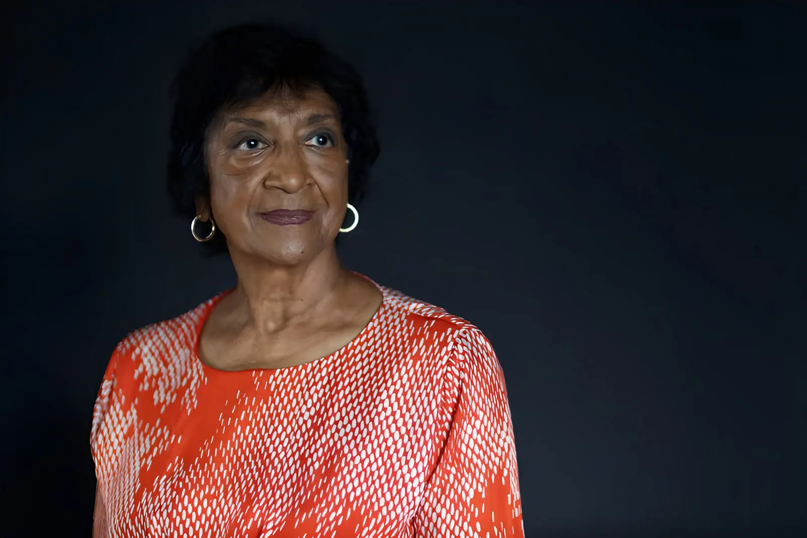 ناوی پیلای (Navi Pillay) با لبخندی ملایم در مقابل پس‌زمینه تیره